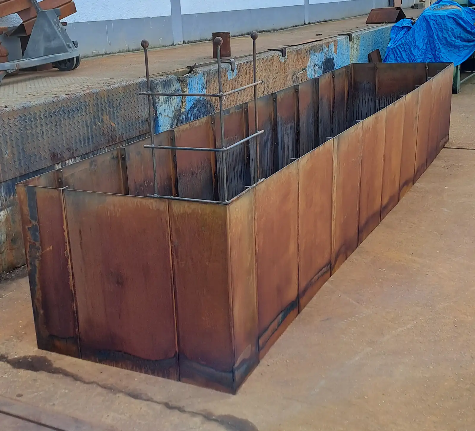 Hochbeet aus 4 mm Cortenstahl, 450x100 cm, 80 cm hoch, mit vormontiertem Rankgitter in der Ecke.